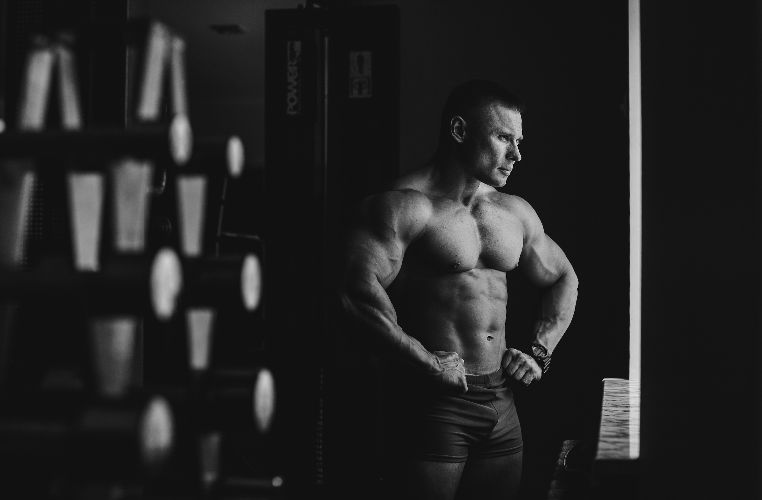 Muscular man posing in a gym with weights in the background